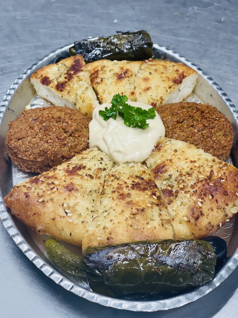 A silver mezze platter with falafel, hummus, dolma and herbed flatbread
