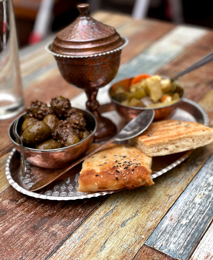 Trio Entrées — copper cups of marinated olives and Persian pickles with wedges of sesame barbari flatbread