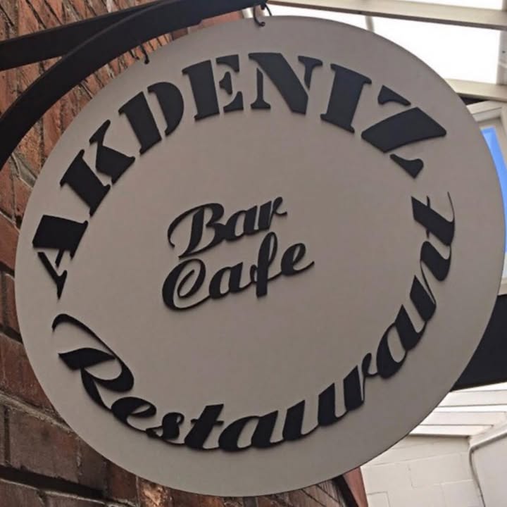 The round AKDENIZ Bar Cafe Restaurant signboard mounted on the red-brick wall at the entrance