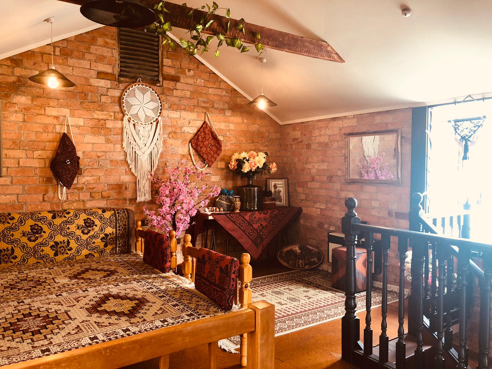 The cosy upstairs Persian seating nook at Akdeniz — exposed brick, kilim cushions, a carpet-covered table and a pink blossom branch